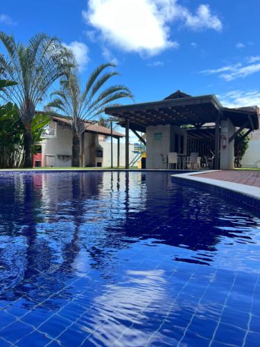 a swimming pool in front of a house with palm trees at Porto Plaza Flat Service Apt 309 in Porto De Galinhas