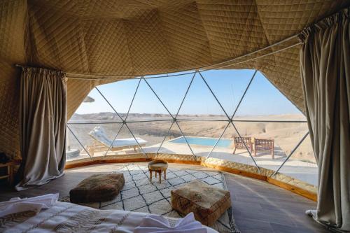 a bedroom with a large window in a tent at The Orion Dome in El Karia