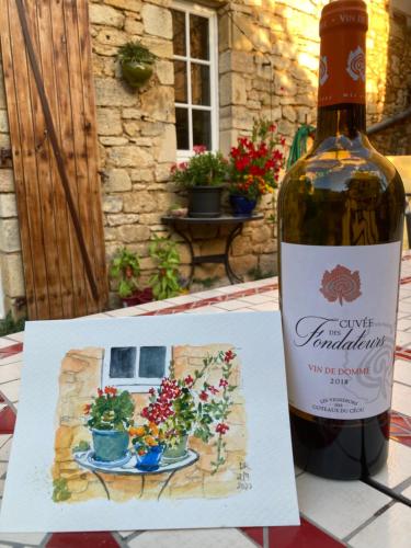 a bottle of wine sitting next to a picture of flowers at Les Petits Cousins Du Québec - Chambres D’hôtes à Domme in Domme