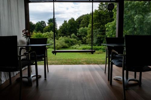 a room with tables and chairs and a large window at Plitvice Inn in Jezerce