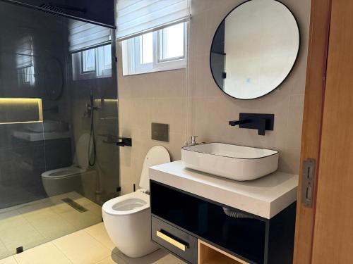 a bathroom with a sink and a toilet and a mirror at R&R Homes in Kwedonu