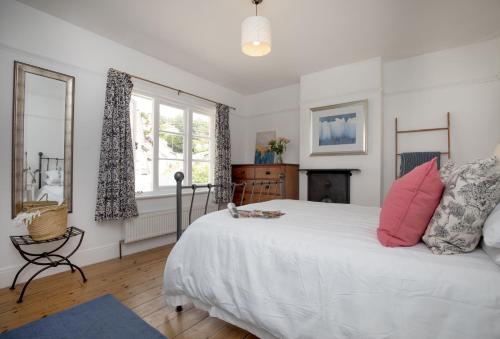 a bedroom with a large white bed with pink pillows at Withycombe in Seaton