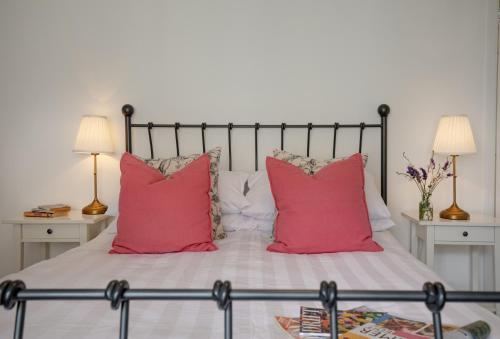 a bed with two red pillows and two lamps at Withycombe in Seaton