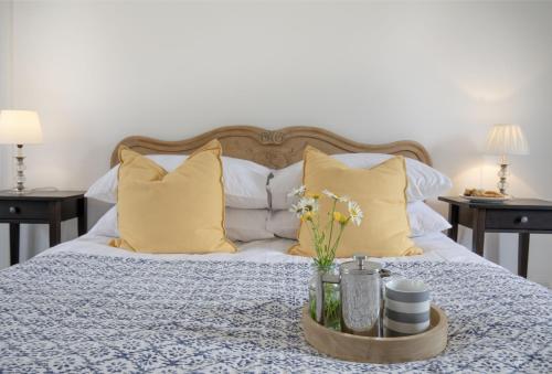 a bed with yellow pillows and a tray with flowers on it at Withycombe in Seaton
