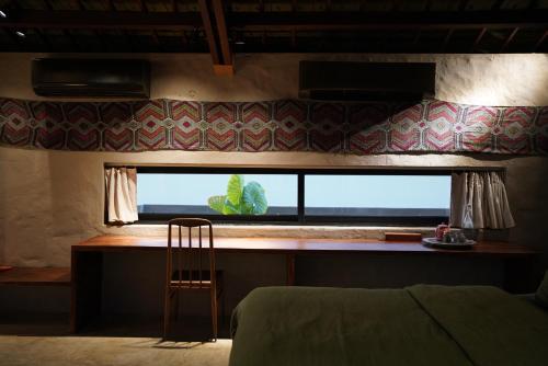 a bedroom with a window with a chair and a table at Dechiu in Hoi An