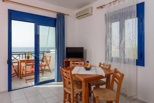 a dining room with a table and chairs and a balcony at Finikas Studios & Apartments - Kalamaki Holidays in Kalamaki