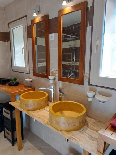 a bathroom with two sinks and two mirrors at GITE de THOMAS in Sarlande