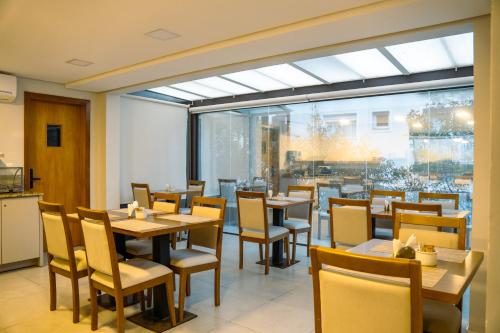a restaurant with tables and chairs and a large window at Pousada Zammá Gramado in Gramado