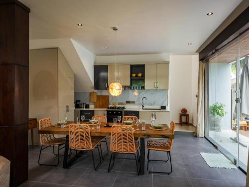 a kitchen and dining room with a wooden table and chairs at Emerald Villas by Paje Emerald Escapes Ltd in Paje