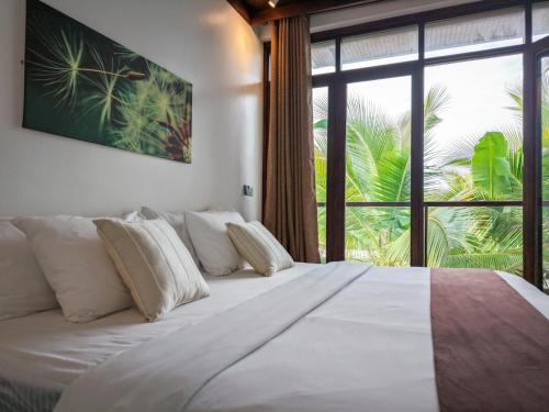 a large bed in a room with a large window at Emerald Villas by Paje Emerald Escapes Ltd in Paje