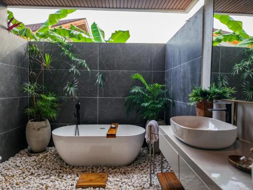 a bathroom with a large bath tub and plants at Emerald Villas by Paje Emerald Escapes Ltd in Paje