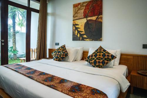 a bedroom with a large white bed with pillows at Emerald Villas by Paje Emerald Escapes Ltd in Paje