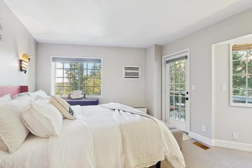 a white bedroom with a bed and two windows at Lakeview Lookout in Skyforest