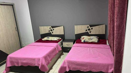 two beds in a room with pink sheets at Dar Hadla in 6th Of October