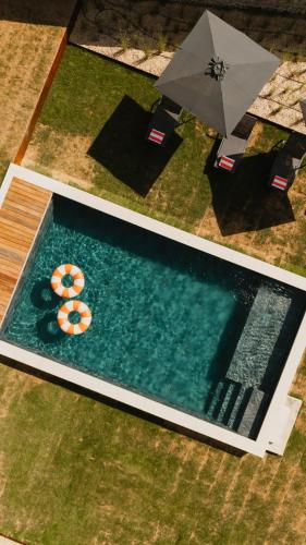 - une vue sur la piscine avec deux parasols dans l'établissement Le Clos des Martines, Maison d'exception, à Écos