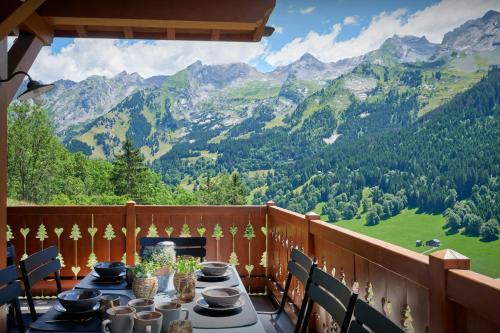 Una mesa en un balcón con vista a las montañas. en Cluzel Alpine Loft - OVO Network, en La Clusaz