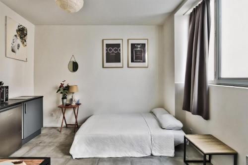 een witte slaapkamer met een bed en een tafel bij O Garibaldi in Lyon