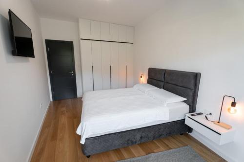 Apartman VISTA FIUME في تريبينيي: غرفة نوم مع سرير أبيض مع اللوح الأمامي الأسود