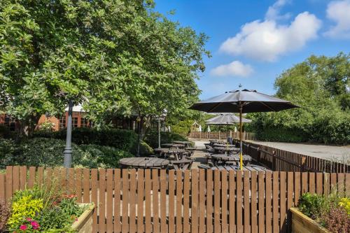 a wooden fence with tables and an umbrella at Sparrow Hotel in Ansty