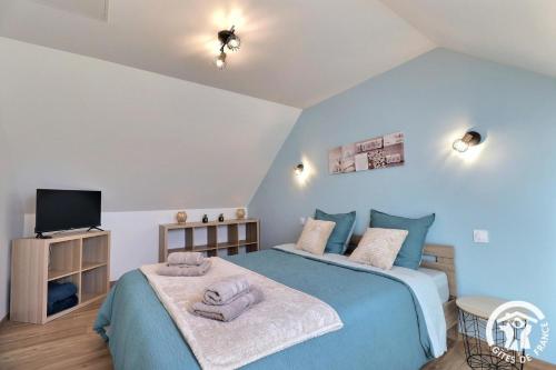 a bedroom with a blue bed and a tv at Le petit paradis de broceliande in Iffendic