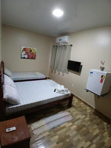 a small room with a bed and a refrigerator at Pousada Criativa in Salinópolis