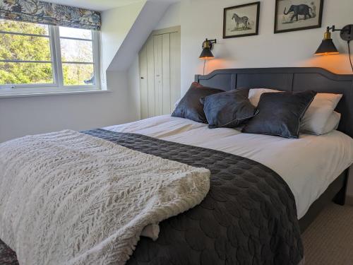 a bedroom with a large bed and a window at Fig Tree Cottage - Corfe Castle in Corfe Castle