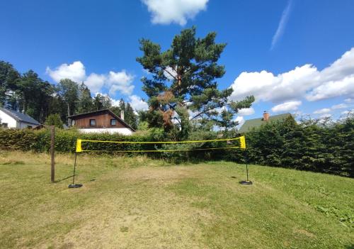 a yellow volleyball net in a field with a tree at Chata Březka in Libuň