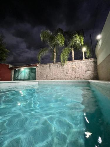 a swimming pool at night with palm trees at Bonita casa con alberca en Mazatepec, Morelos in Mazatepec