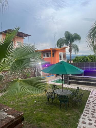 a table and chairs with a green umbrella at Bonita casa con alberca en Mazatepec, Morelos in Mazatepec