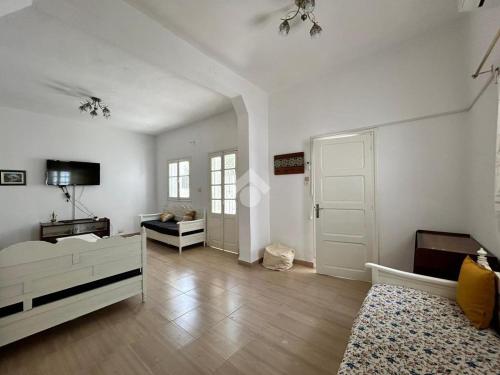 a white room with a bed and a tv and a door at Villa atypique Sousse Quartier chic in Sousse