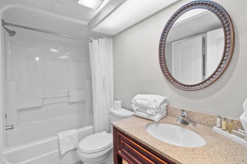 a bathroom with a sink and a toilet and a mirror at Monterey Bay Suites in Myrtle Beach