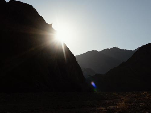 the sun shining through the mountains in the desert at Natural Lodge in Dahab