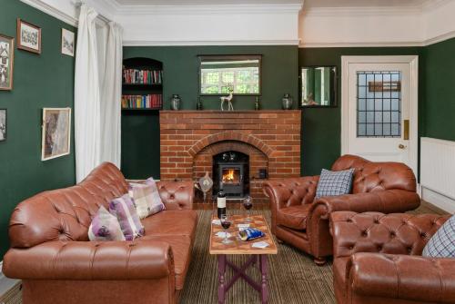 a living room with leather furniture and a fireplace at The Hunters Inn in Martinhoe
