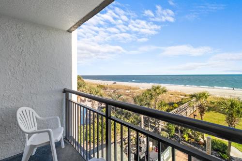 a balcony with a chair and a view of the beach at Monterey Bay Suites in Myrtle Beach
