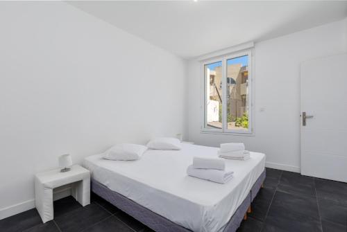 une chambre blanche avec un grand lit et une fenêtre dans l'établissement Moneghetti, à Beausoleil