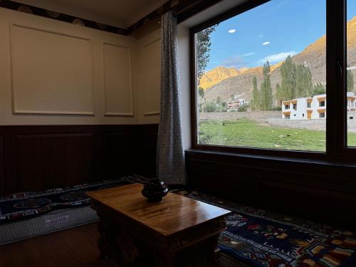a room with a large window and a wooden table at New Royal Guest House in Leh