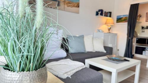 a living room with a couch and two potted plants at MEERzeit in Westerland (Sylt)