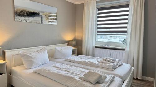 a bedroom with two beds with white sheets and a window at MEERzeit in Westerland (Sylt)