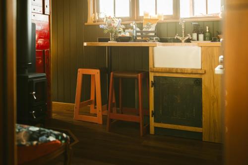 a kitchen with a sink and a counter with two stools at Sycamore and Stars Off Grid Retreat in Grasby