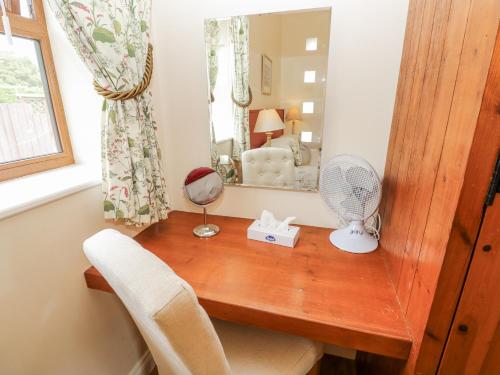 a room with a desk with a fan and a mirror at 2 The Stables in Haven Street