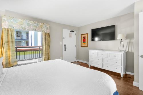 a bedroom with a white bed and a flat screen tv at Monterey Bay Suites in Myrtle Beach