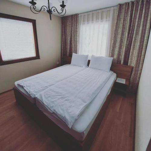 a bedroom with a bed with white sheets and a window at Konak Hilltop Lodge & Villa in Kruševo