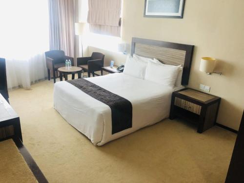 a hotel room with a large bed and chairs at Hotel Felda Residence Kuala Terengganu in Kuala Terengganu
