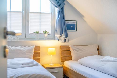 two twin beds in a room with a window at Windrose in Greetsiel