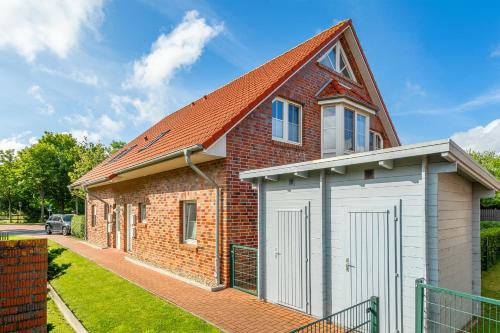 a red brick house with a white garage at Heubude in Greetsiel