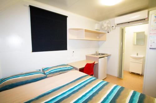 a bedroom with a bed and a desk and a television at Meekatharra Accommodation Centre in Meekatharra