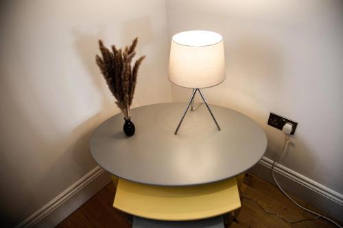 a table with a lamp on top of a yellow chair at Academy Apartments By Elegance Stays in Hull