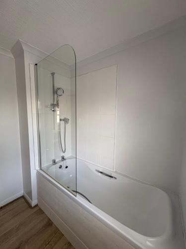 a white bathroom with a tub with a glass shower at Serenity Lodge, Riverside with Free Parking in Christchurch