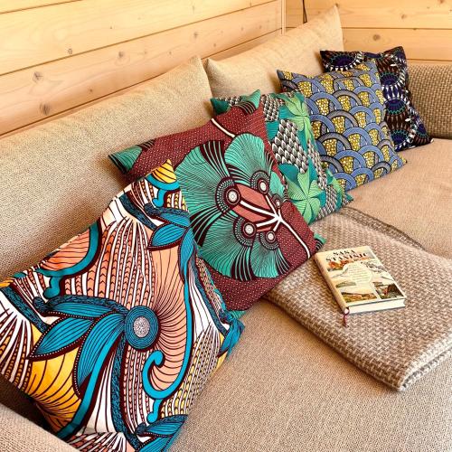 a colorful pillow on a couch with a book at 208-Tiny House an der Elbe mit Blick ins Grüne in Bleckede
