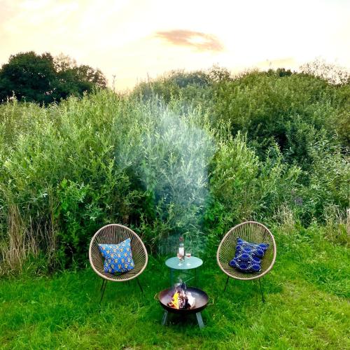 two chairs and a table with a fire in the grass at 208-Tiny House an der Elbe mit Blick ins Grüne in Bleckede